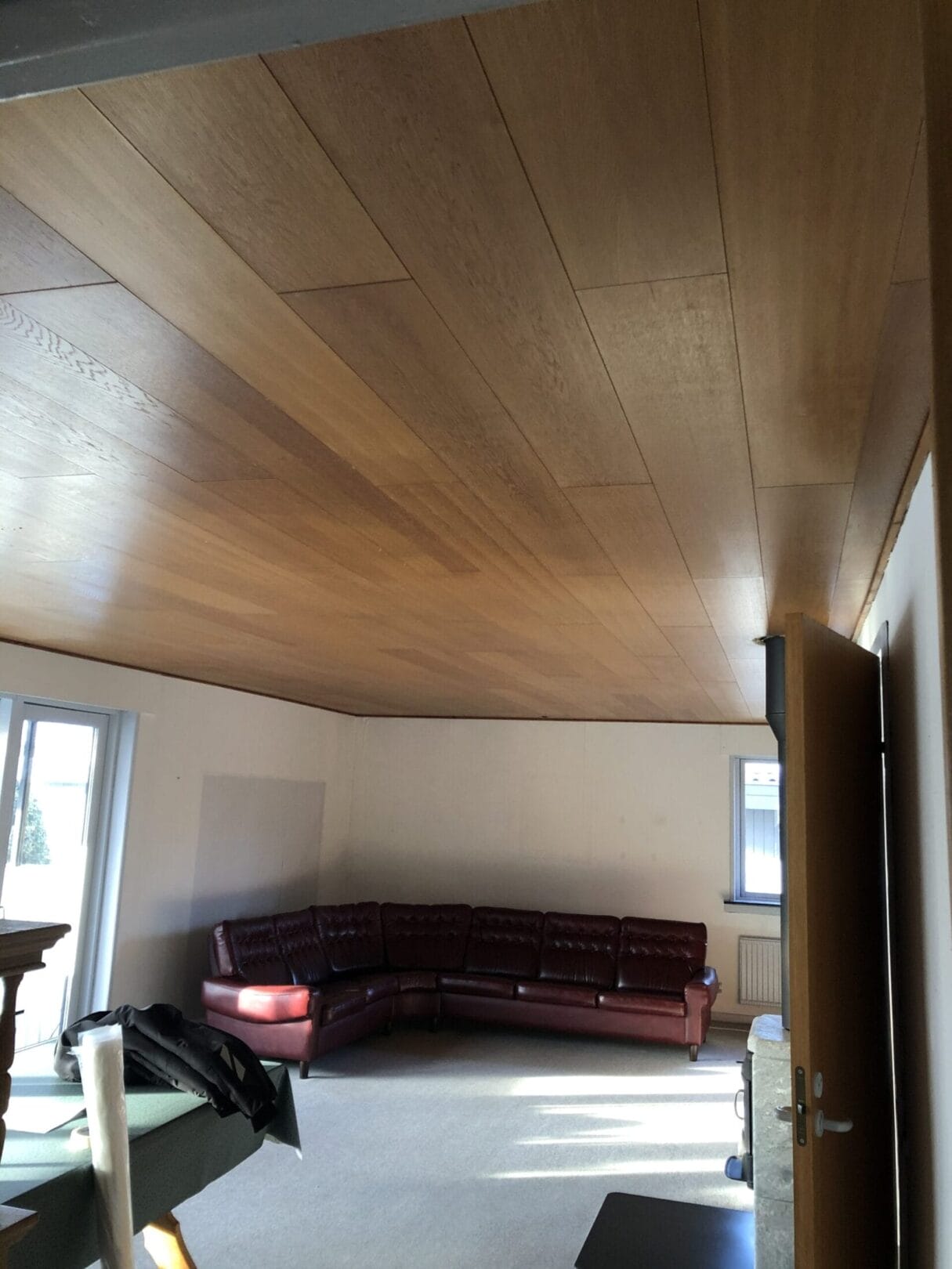 Stue med træloft og rød lædersofa